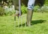 Close-up of gardener’s booted foot using garden fork to aerate lawn