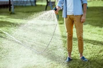 A man using a sprinkler attachment to water the lawn