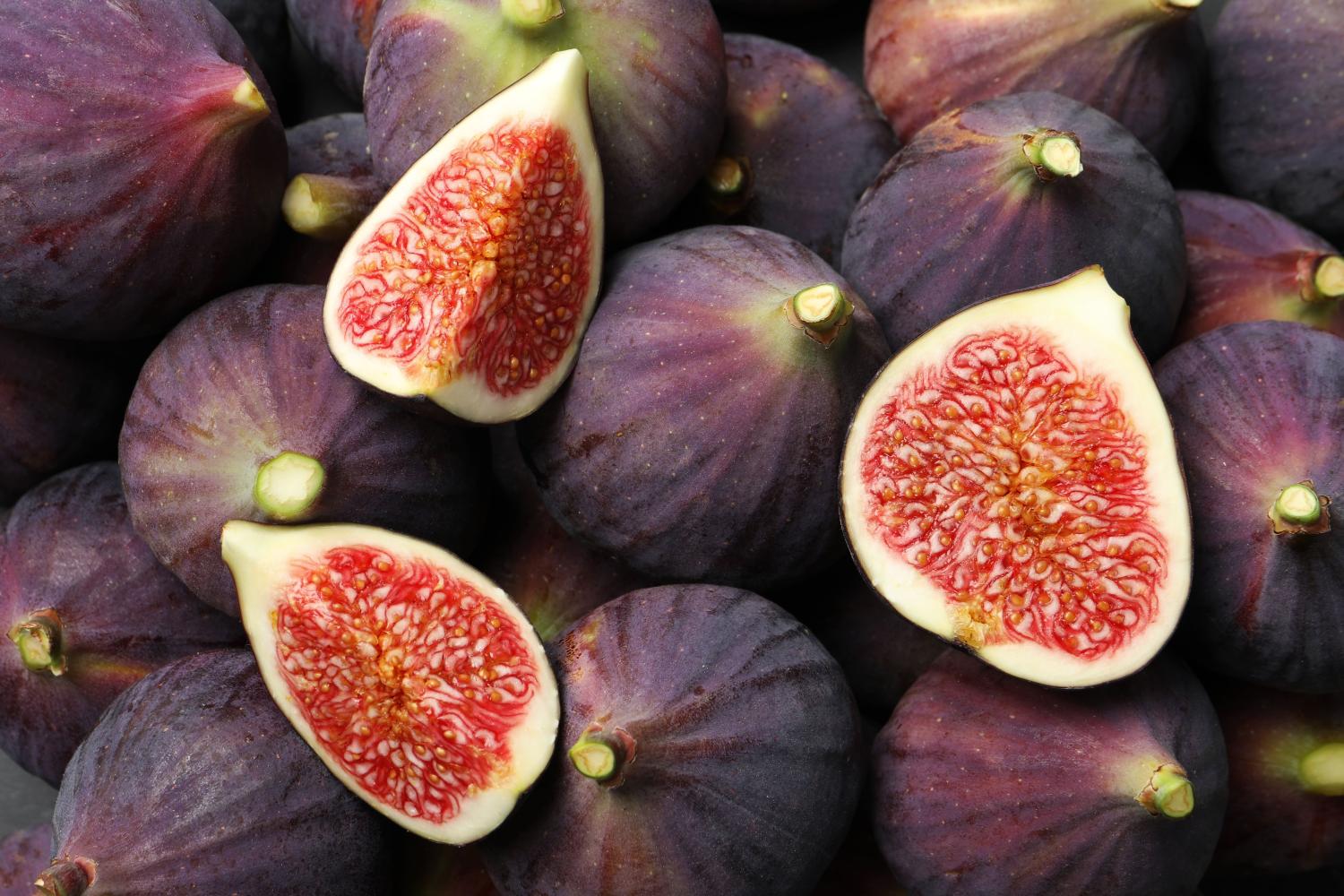 Bowl of ripe figs with three figs cut open.